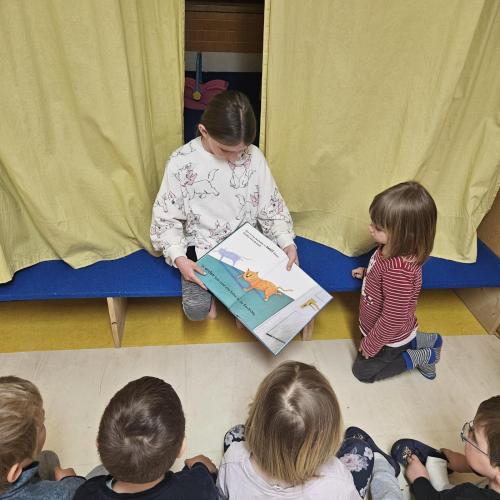 Mädchen liest Kindern im Kindergarten vor