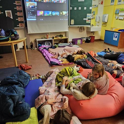 Kinder in ihren Schlafsäcken am Boden freuen sich auf den Film an der Leinwand
