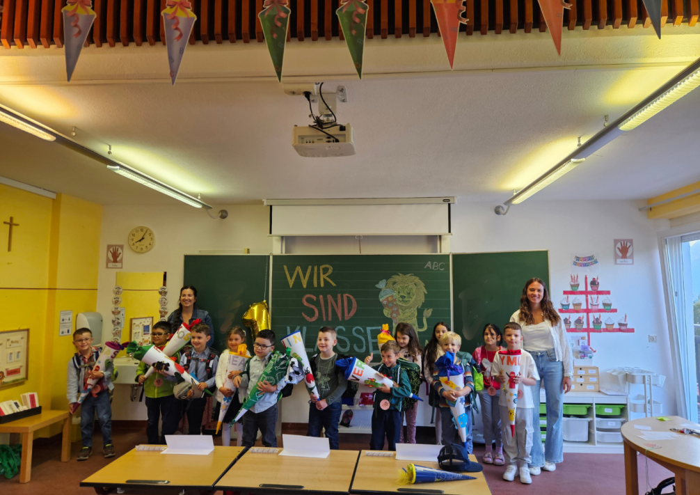 Kinder vor der Tafel mit Schultüten mit ihren Lehrerinnen